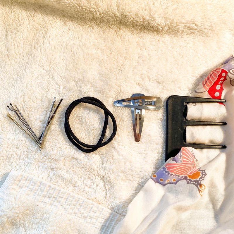 hair accessories arranged to spell vote, bobby pins, hair ties and comb