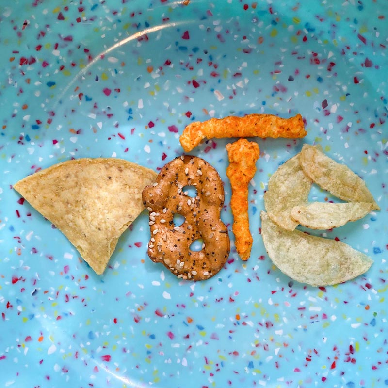 salty snacks arranged to spell vote, torilla chip, pretzel, cheetos and potato chips