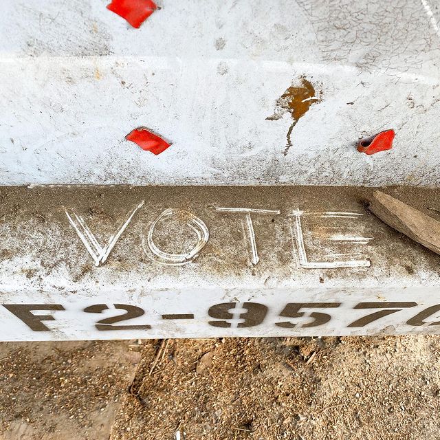 Vote spelled by wiping dirt off of a city dumpster